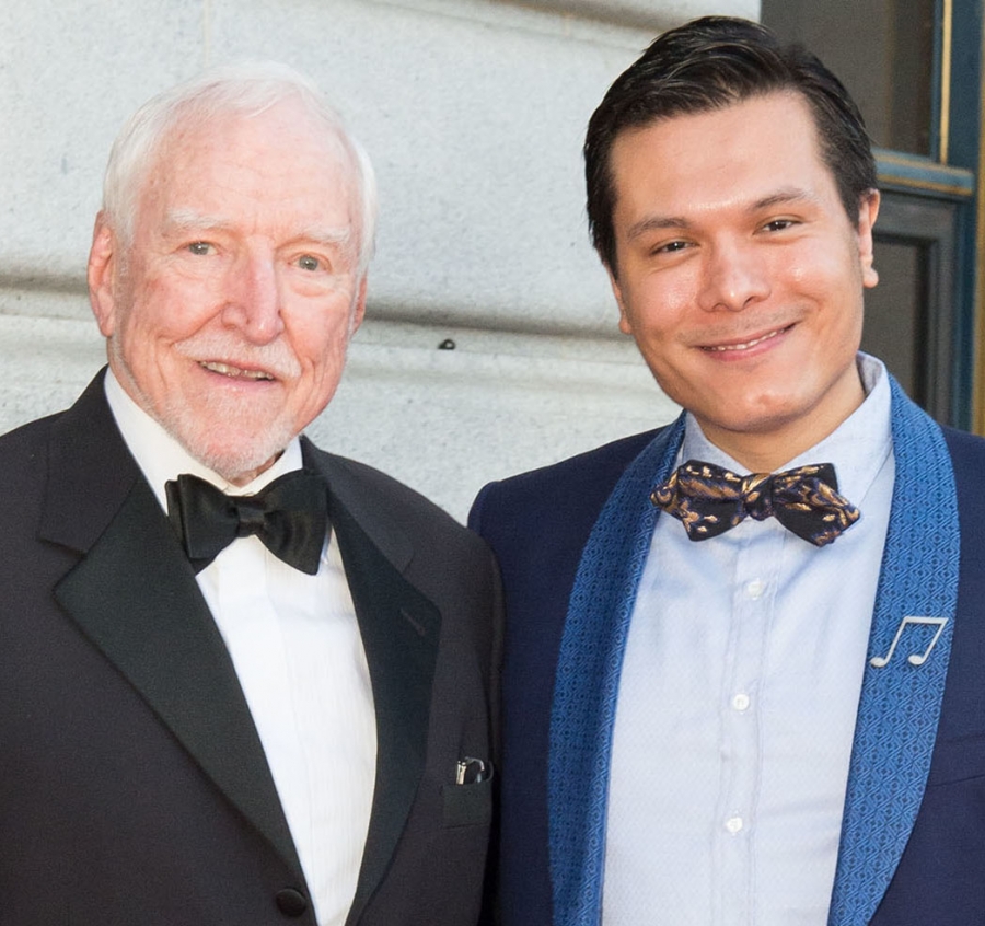 two men stand together on a red carpet